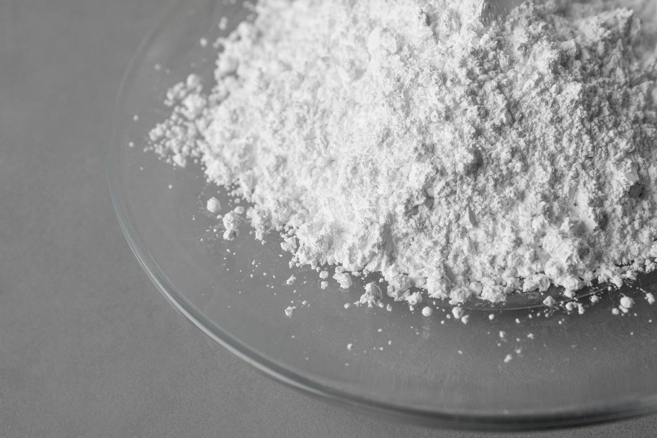 Plate with Calcium Carbonate Powder on Grey Table, Closeup